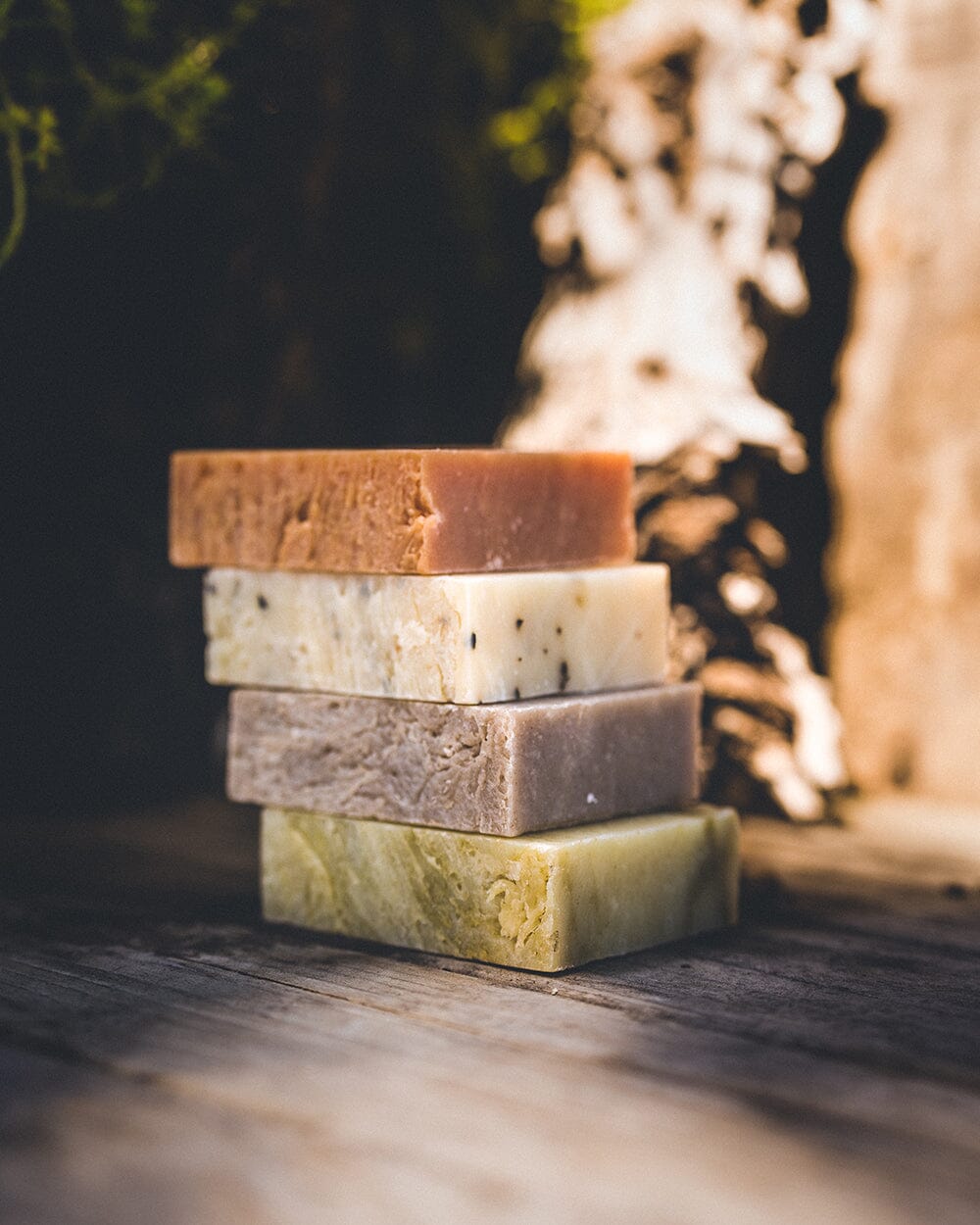 A layered stack of 4 all natural soap bars from Iron Lion Soap resting on a wood table 