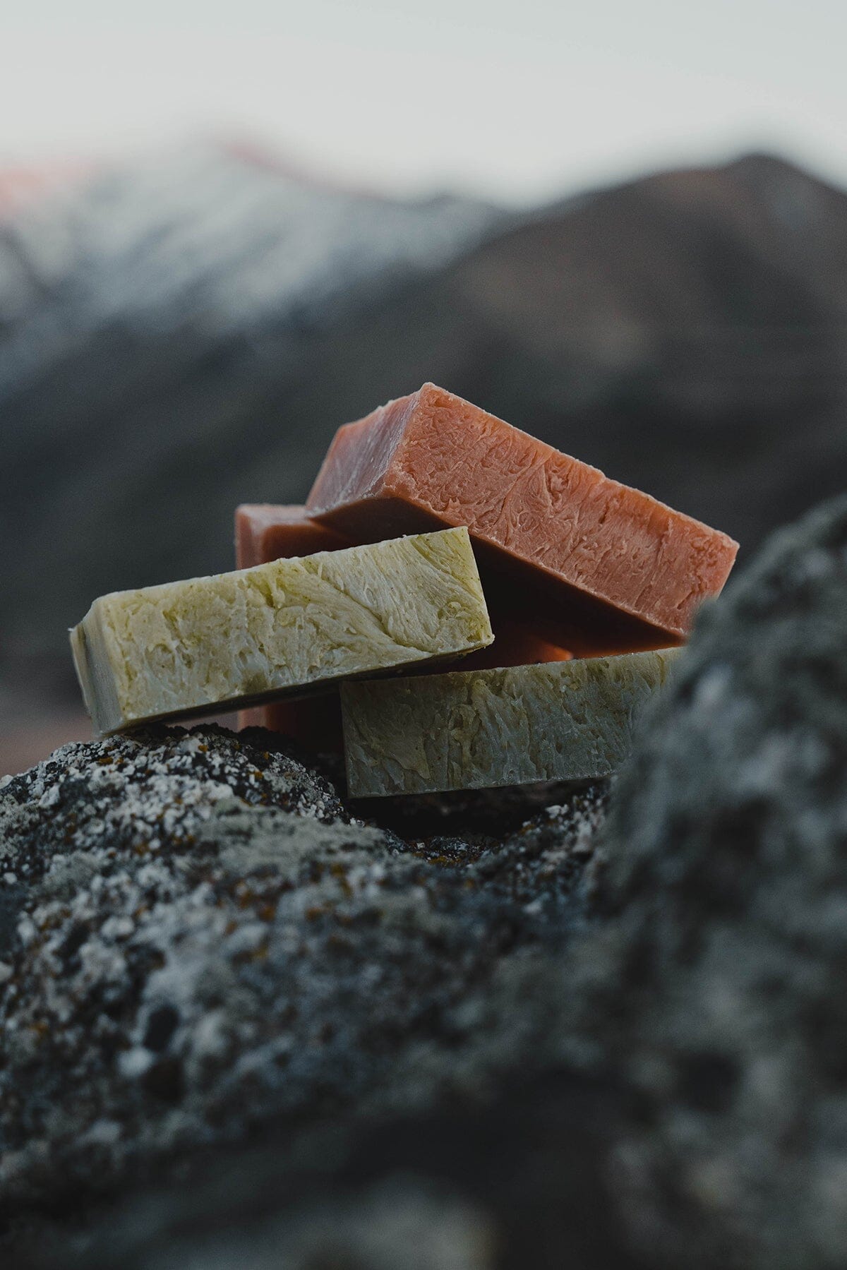 A stack of three all natural, organic soap bars made with essential oils from Iron Lion Soap on a rocky mountain's edge.