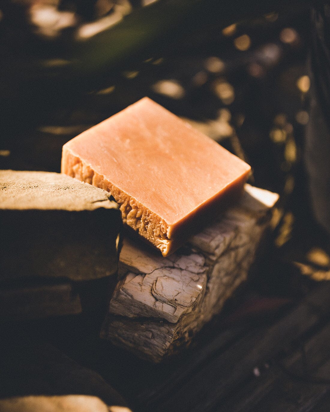  A bar of all-natural, anti-fungal, anti-bacterial soap from Iron Lion Soap placed on a rock near a garden bed.